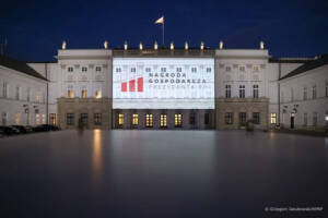 Pałac w nocy, na jego ścianie jest projekcja obrazu z logiem i napisem, Nagroda gospodarcza prezydenta RP