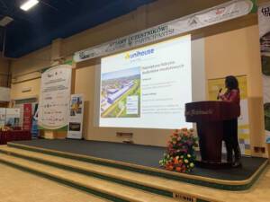 prezenterka i jej prezentacja, slajd mówi o największej fabryce materiałów budowlanych firmy unihouse